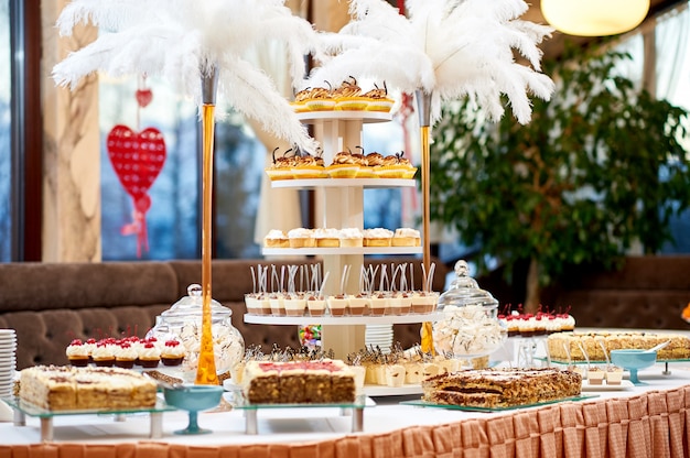 Disparo de una mesa de restaurante con un montón de diferentes postres sabrosos cupcakes y pasteles cremosos de azúcar dulce comer café concepto de celebración.