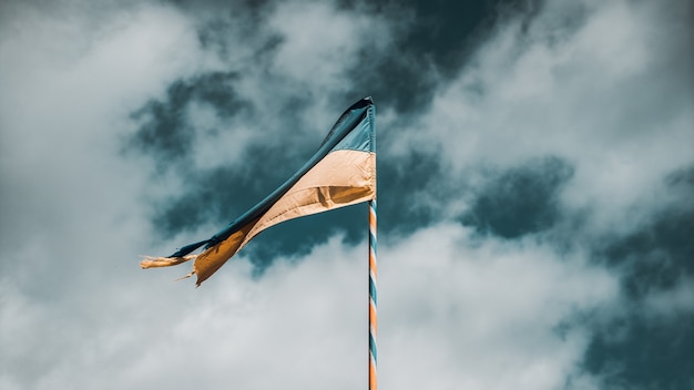 Disparo selectivo de la bandera amarilla y azul de Ucrania en asta de bandera en el fondo de un cielo nublado