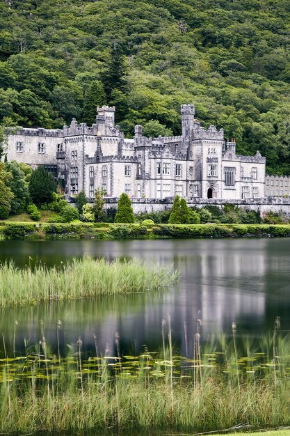 Disparo vertical de la Abadía de Kylemore en Irlanda rodeada de vegetación y un lago