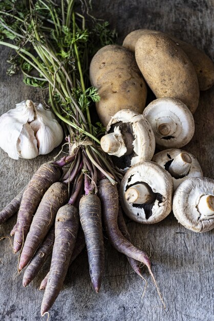 Disparo vertical de ajo, patatas, champiñones y zanahorias sobre una superficie de madera