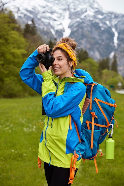 Disparo vertical de alegre viajero femenino se centra en la vista panorámica de la naturaleza