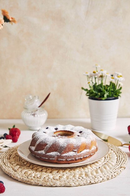 Disparo vertical de un anillo de pastel con frutas y polvo sobre una mesa blanca