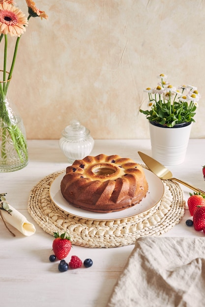 Disparo vertical de un anillo de pastel con frutas sobre una mesa blanca con fondo blanco.