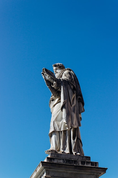 Disparo vertical de una antigua estatua histórica tocando el cielo azul claro