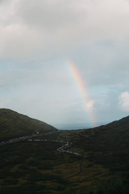 Disparo vertical de un arco iris en el valle de la montaña con un cielo nublado