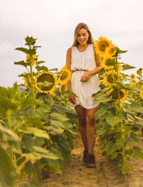 Disparo vertical de una atractiva mujer rubia en un campo de girasoles bajo la luz del sol