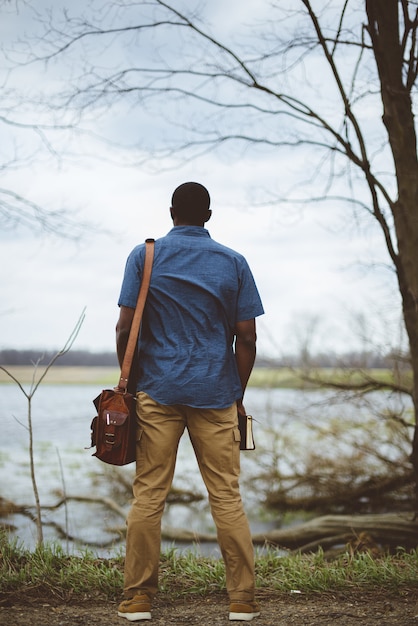 Foto gratuita disparo vertical desde atrás de un hombre con una bolsa y sosteniendo la biblia