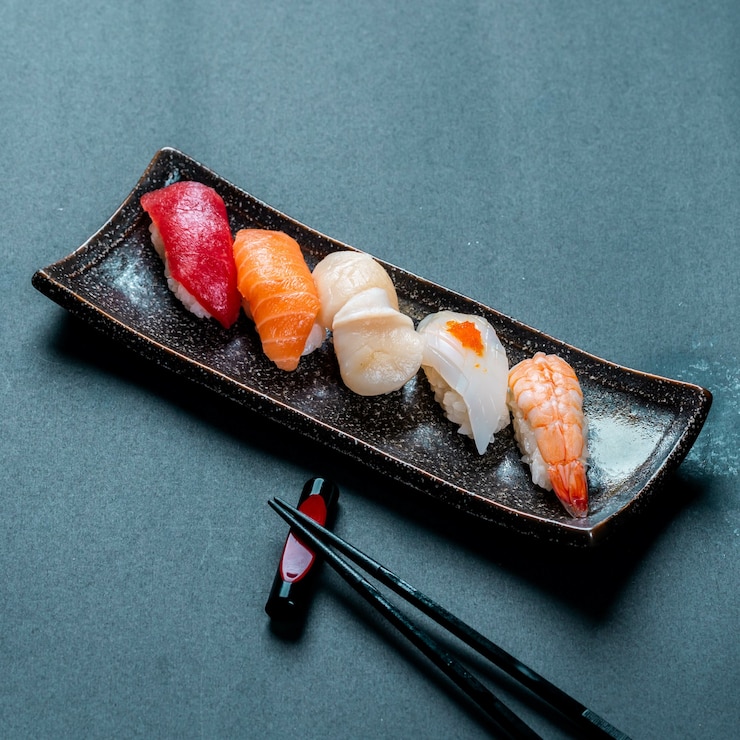Foto gratuito disparo vertical de atún fresco, salmón, vieira, nigiri y sushi de camarones y palillos