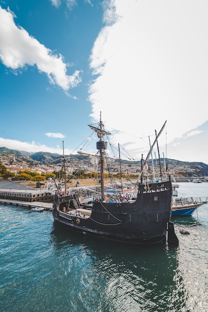 Disparo vertical de un barco de madera en el agua cerca del muelle en Funchal, Madeira, Portugal.