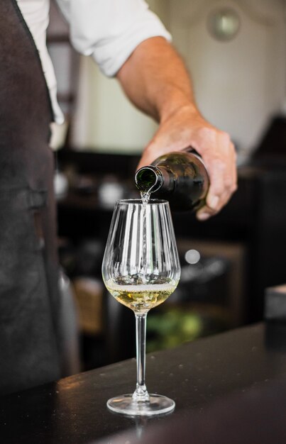 Disparo vertical de un barman vertiendo un vino en un vaso