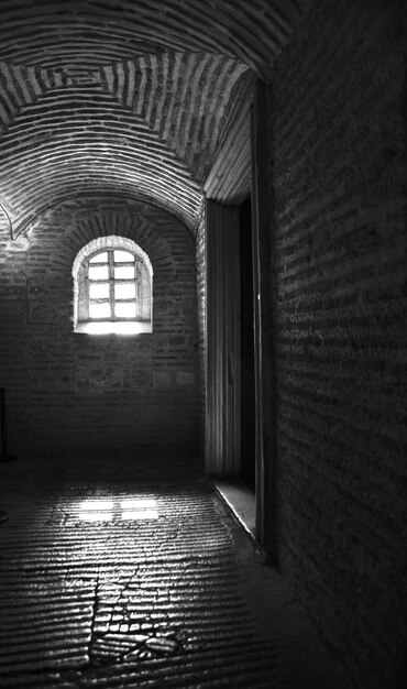 Disparo vertical en blanco y negro del interior de un edificio con una ventana durante el día