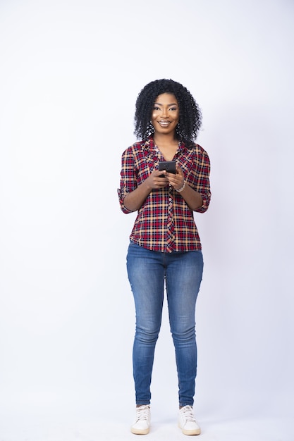 Disparo vertical de una bonita mujer negra sonriendo mientras usa su teléfono