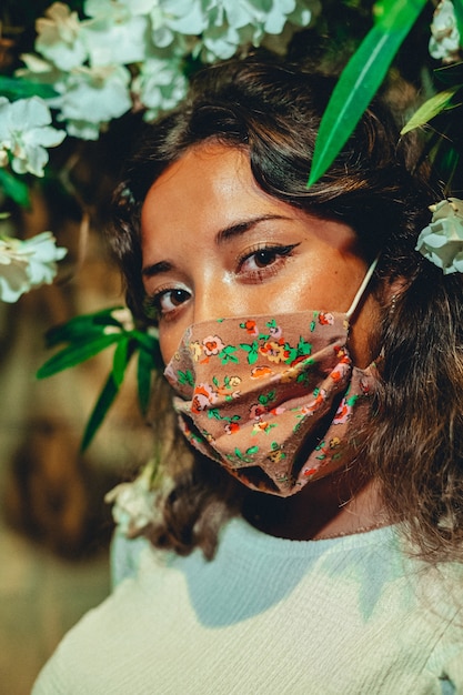 Disparo vertical de bronceada hembra europea vistiendo una máscara floral en un parque de atracciones