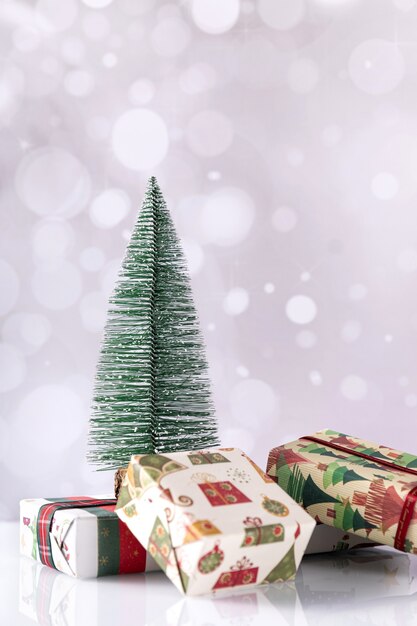 Disparo vertical de cajas de regalo de Navidad y árbol pequeño en bokeh