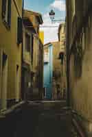 Foto gratuita disparo vertical de un callejón vacío alineado con viejos edificios amarillos que conducen a un edificio azul