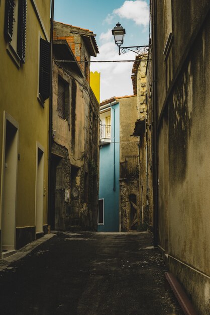 Disparo vertical de un callejón vacío alineado con viejos edificios amarillos que conducen a un edificio azul