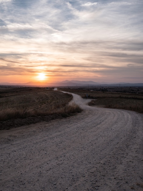 Disparo vertical de un camino en un campo de hierba con la impresionante vista del atardecer en el