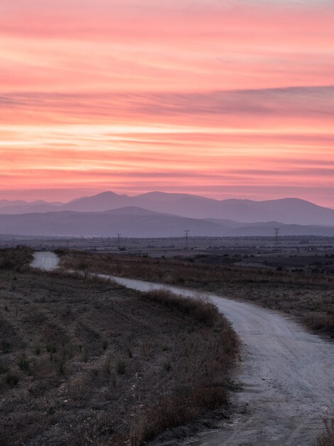 Disparo vertical de un camino en un campo de hierba con la impresionante vista del atardecer