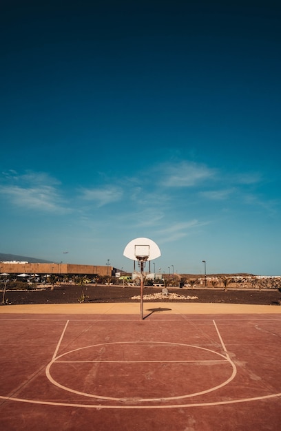 Disparo vertical de una cancha de baloncesto con el aro visible bajo el cielo azul