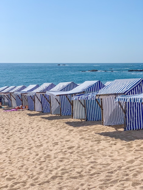 Disparo vertical de carpas de playa de rayas azules y blancas en Portugal
