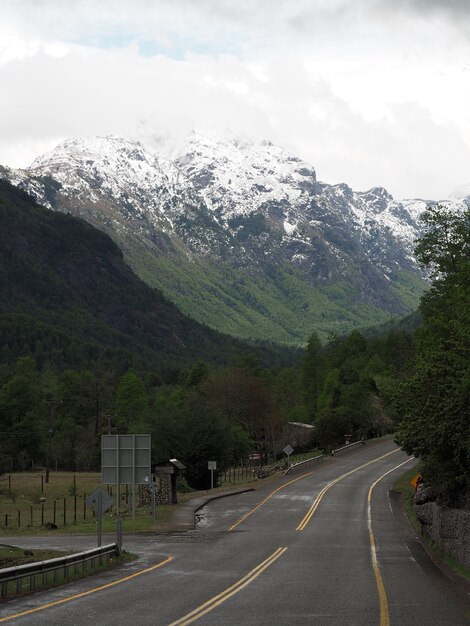 Disparo vertical de una carretera y montañas cubiertas de árboles con picos nevados