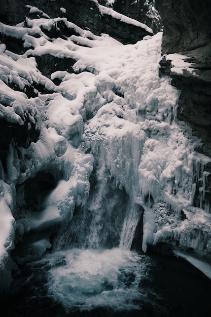 Disparo vertical de la cascada congelada rodeada de rocas en invierno