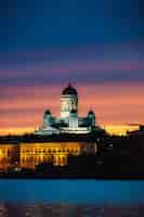 Foto gratuita disparo vertical de la catedral de helsinki rodeada de luces durante la puesta de sol en finlandia