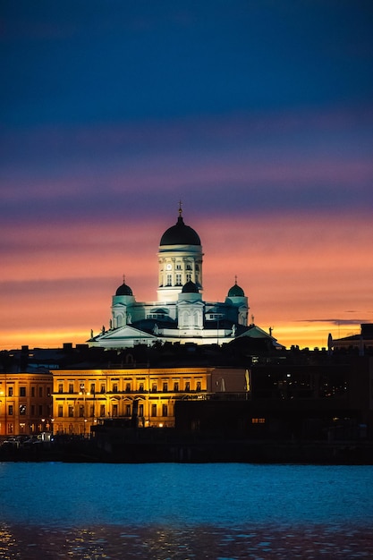 Disparo vertical de la Catedral de Helsinki rodeada de luces durante la puesta de sol en Finlandia