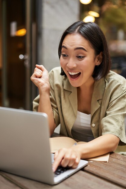 Disparo vertical de una chica feliz hablando por videollamada mira la computadora portátil que tiene una reunión en línea sentada en o