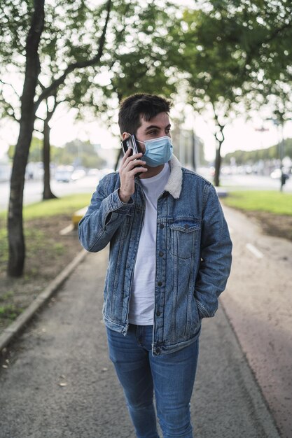 Disparo vertical de un chico con una camiseta con una chaqueta de jeans, pantalones y una máscara sanitaria