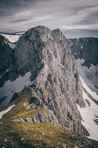 Disparo vertical de colinas rocosas cubiertas de nieve bajo un cielo nublado en el campo