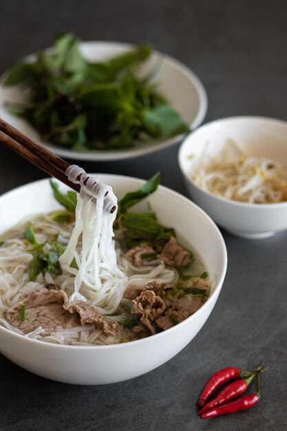 Disparo vertical de comida vietnamita, sopa Pho Bo con chiles rojos sobre la mesa