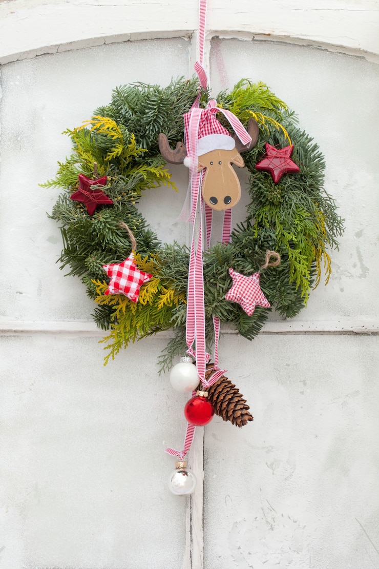 Foto gratuito disparo vertical de una corona de navidad decorativa con adornos colgando de una puerta blanca