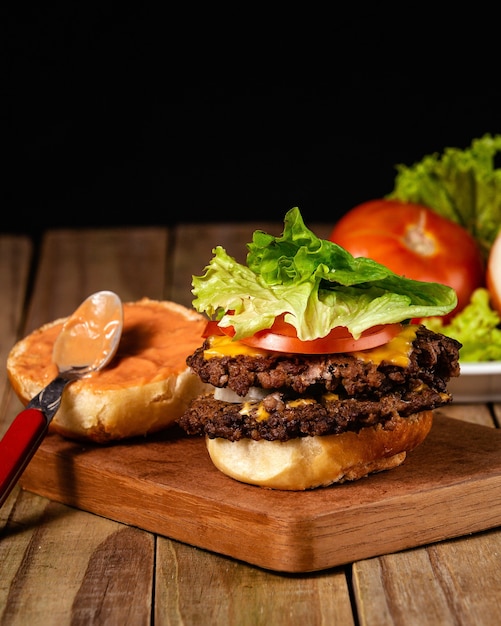 Disparo vertical de una deliciosa hamburguesa con la salsa del pan sobre una tabla de madera