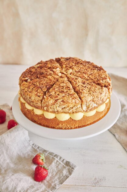 Disparo vertical de una deliciosa tarta de crema con almendras crujientes y fresas en un soporte para tartas