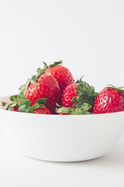 Disparo vertical de deliciosas fresas frescas en un recipiente blanco