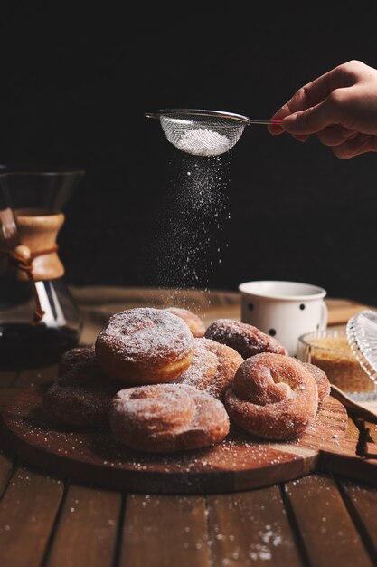 Disparo vertical de deliciosas rosquillas de serpiente espolvoreadas con azúcar en polvo y café chemex