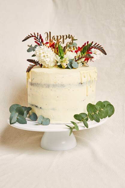 Disparo vertical de un delicioso cumpleaños crema de flores blancas en la parte superior del pastel con un goteo en el lateral