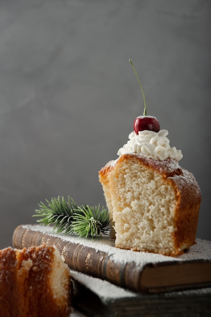 Disparo vertical de delicioso postre con crema, azúcar en polvo y una cereza en la parte superior de los libros