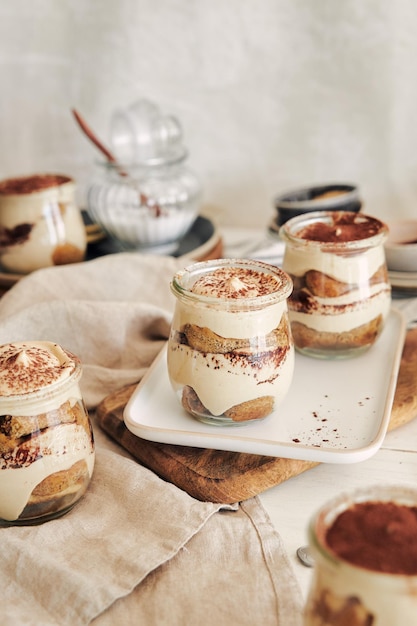 Disparo vertical de delicioso tiramisú en vasitos con polvo sobre una mesa blanca