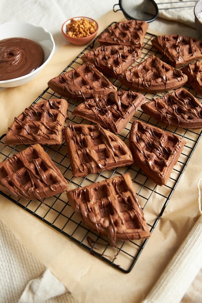 Foto gratuita disparo vertical de deliciosos gofres de chocolate en una red sobre la mesa cerca de los ingredientes