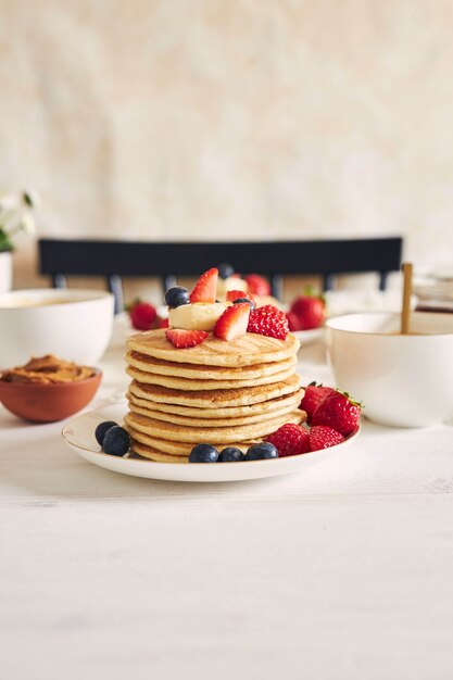 Disparo vertical de deliciosos panqueques veganos con fresas y moras en un plato