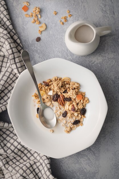 Disparo vertical de un desayuno oaten con frutos secos y frescos cerca de una jarra de leche