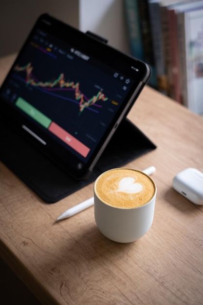 Foto gratuita disparo vertical de un dispositivo de tableta taza blanca de un clásico nescafé cápsulas para los oídos en una mesa de madera