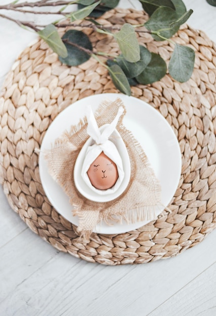 Disparo vertical de una divertida decoración de huevos de Pascua en un plato con hojas verdes