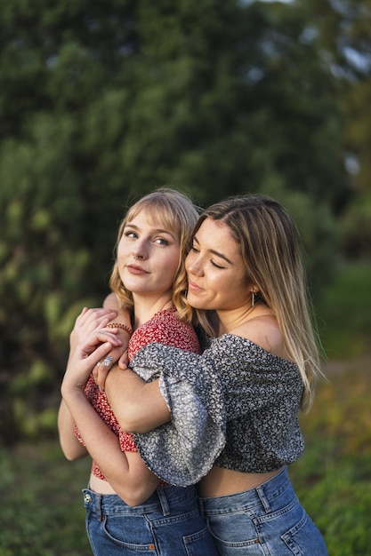 Foto gratuita disparo vertical de dos hermosos amigos caucásicos españoles abrazándose en el parque