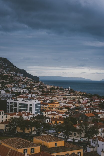 Disparo vertical de edificios en la montaña bajo un cielo nublado en Funchal, Madeira, Portugal.