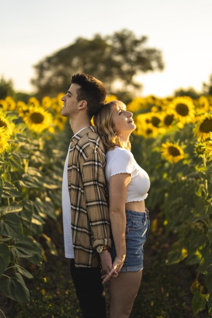 Disparo vertical de una encantadora pareja caucásica en el campo de girasoles en España