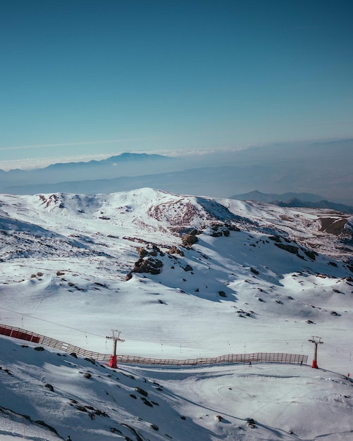 Disparo vertical de una estación de esquí cubierta de nieve bajo la luz del sol y un cielo azul