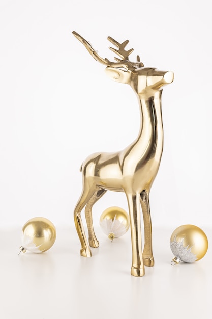 Disparo vertical de una estatua de ciervo dorado con bolas de adorno de Navidad aislado sobre un fondo blanco.